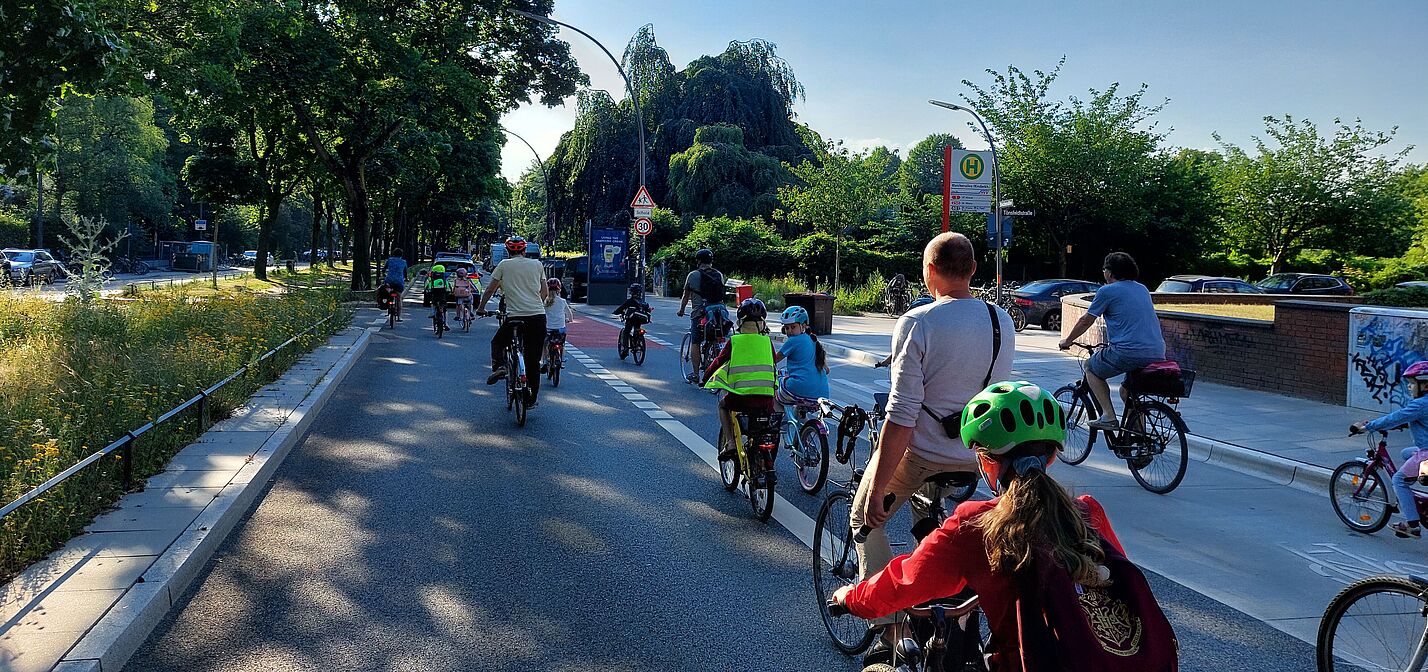 Bicibus Hamburg Eine Gruppe von Kindern fährt auf ihren Rädern auf der Straße. Sie werden von Erwachsenen begleitet.